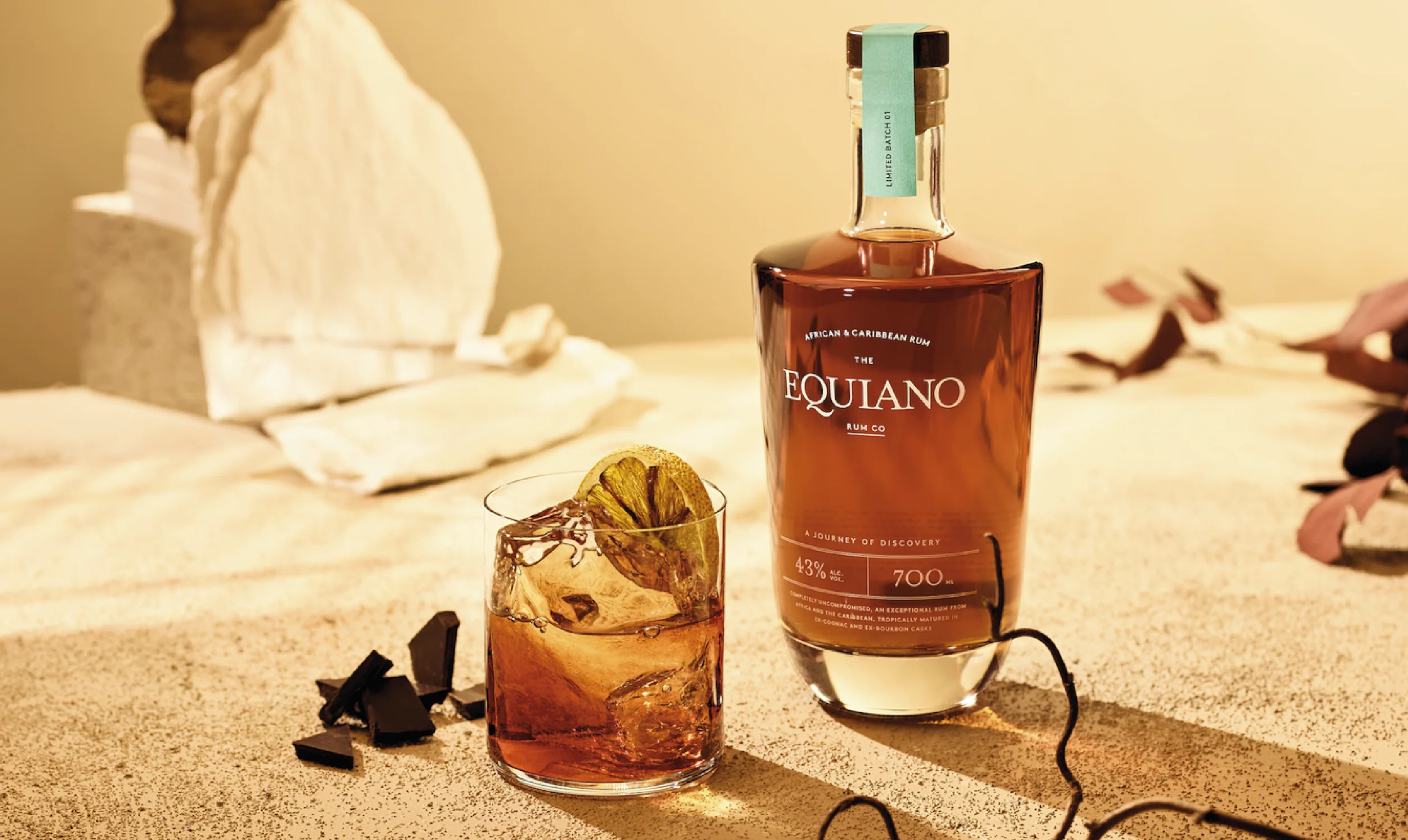 Equiano rum bottle and cocktail in a sunlit tropical landscape.